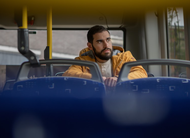 Een man zit in de bus en lijkt diep in gedachtes. 